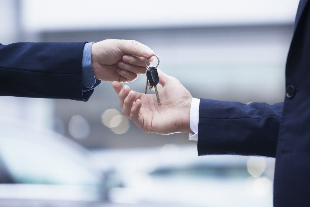car rental serviceman handing keys over to customer