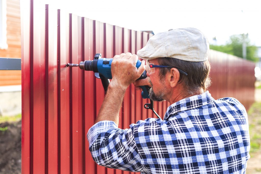 man installing metal fence