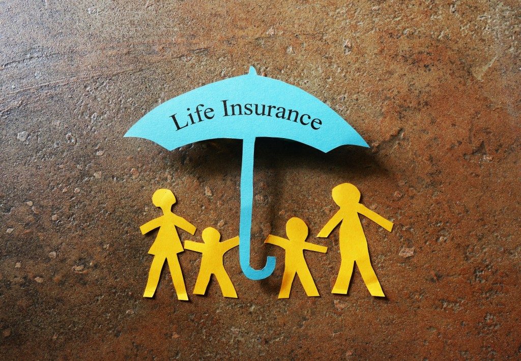 Paper family of four under a Life Insurance paper cutout umbrella