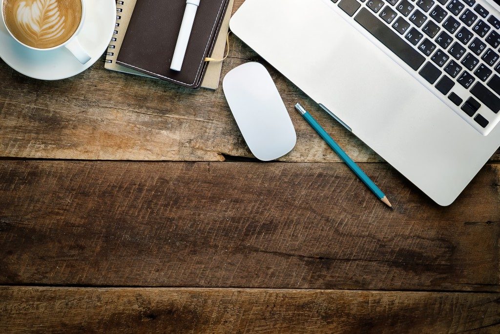 Wood desk with laptop, coffee and notebook on top