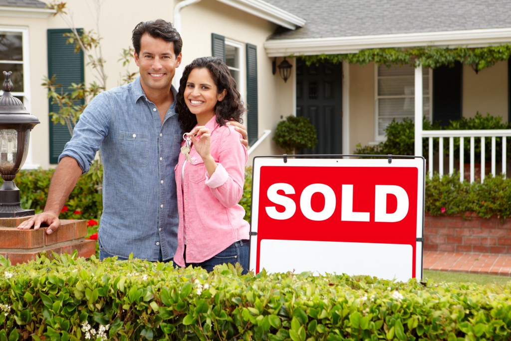 couple posing in front of the house they just bought