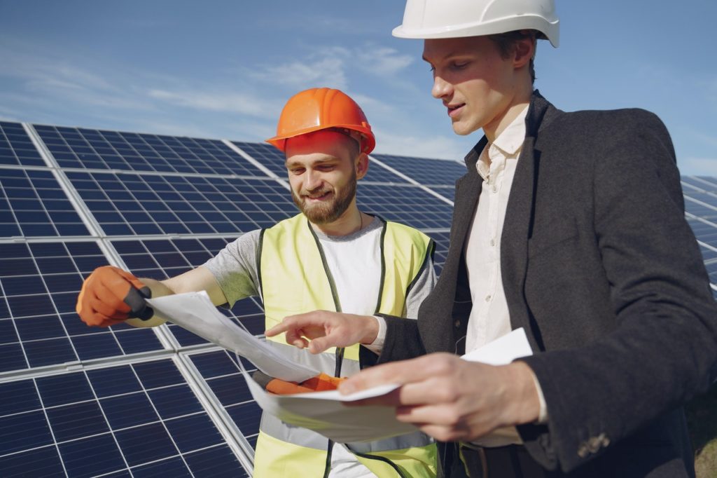 two men in front of some solar panels