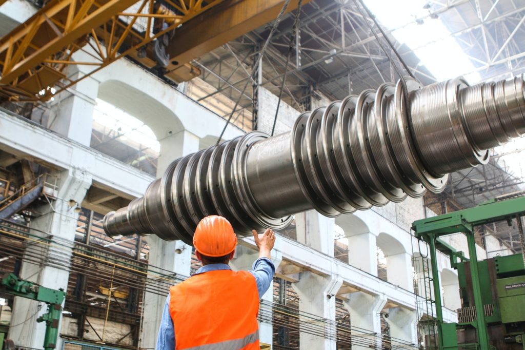 man at a factory looking at a giant metal rod