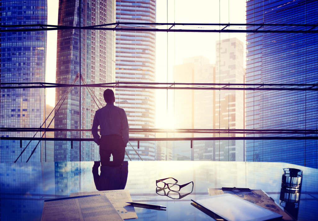 A businessman in an office looking at the cityscape and sunrise