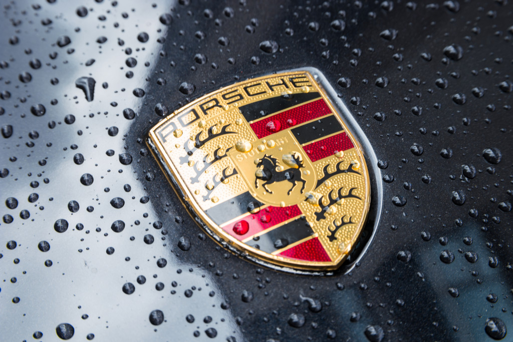 A close-up of the Porsche emblem on the hood of a wet car