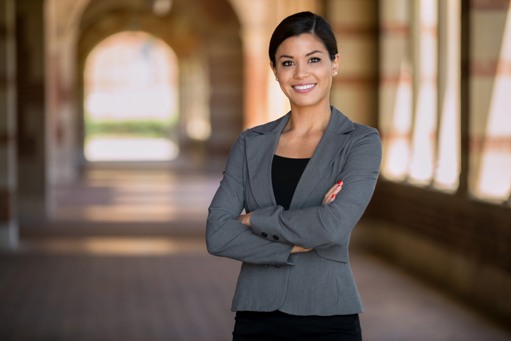 Smiling young businesswoman with her arms folded standing in a hallway.