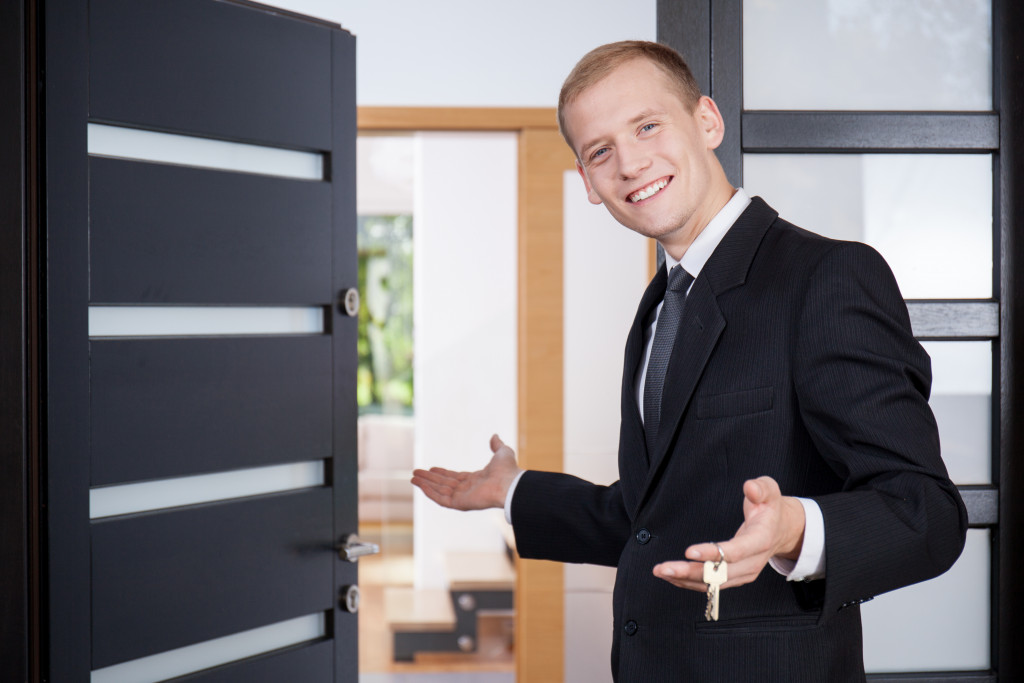 A real estate agent in front of an open house door