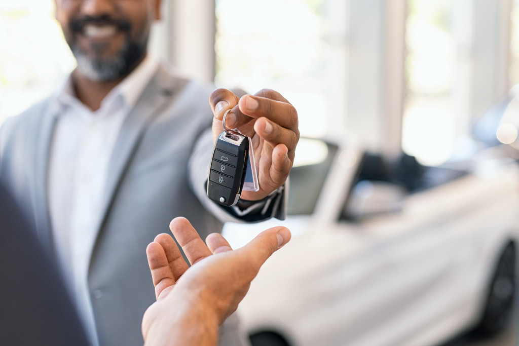 man smiling while handing car keys to potential buyer